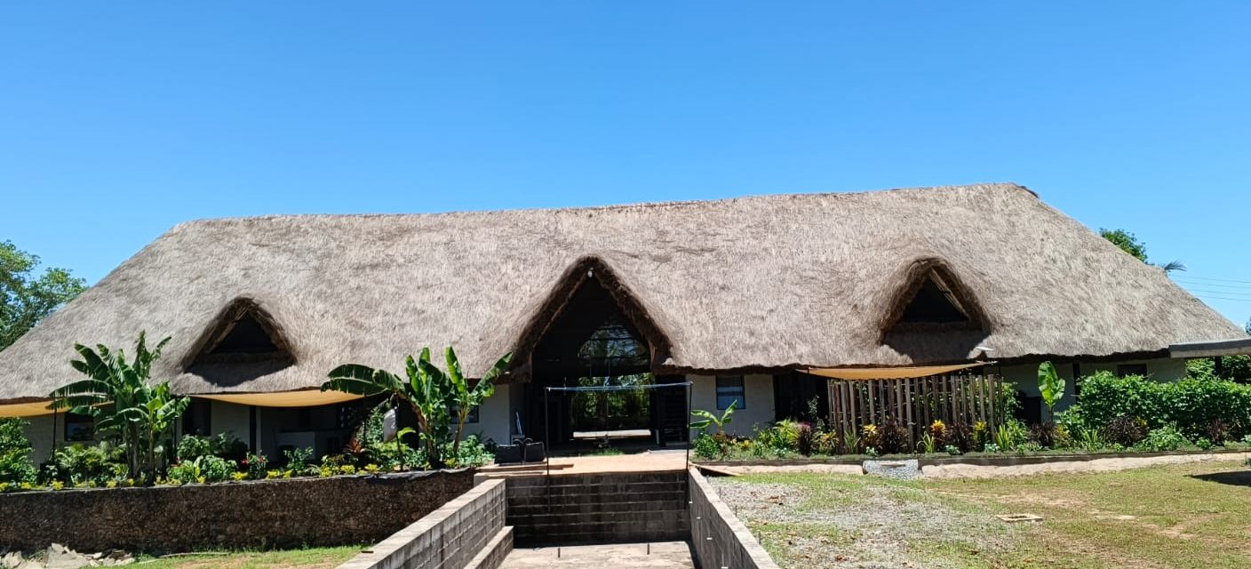 The finished residence — thatched roof complete, gardens planted